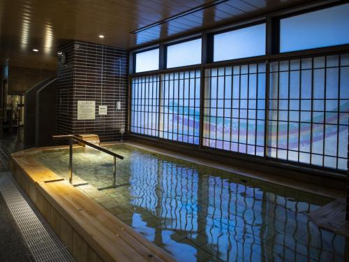 a swimming pool in a building with windows at Onyado Nono Kyoto Shichijo Natural Hot Spring in Kyoto