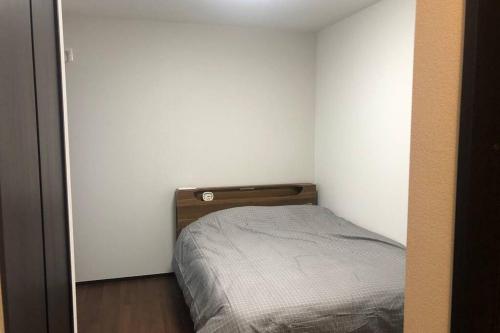 a small bedroom with a bed in a white wall at 玉藻本町103 in Takamatsu