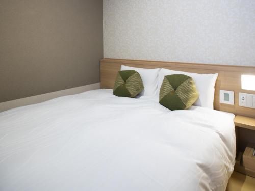 a bedroom with a white bed with two pillows at Onyado Nono Kyoto Shichijo Natural Hot Spring in Kyoto