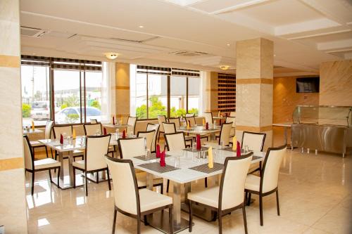 um restaurante com mesas, cadeiras e janelas em HOTEL AFRICANA LSK em Lusaka