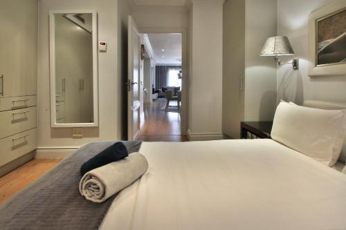 a bedroom with a white bed and a mirror at Cape Royale 2 Bedroom Luxury Apartment with Views in Cape Town