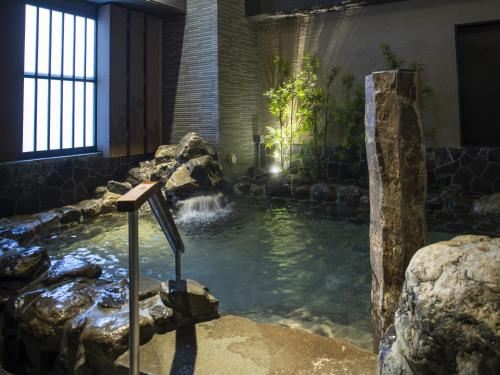 a large pool of water in a room with rocks at Onyado Nono Kyoto Shichijo Natural Hot Spring in Kyoto