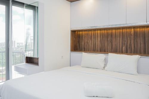 a bedroom with a white bed and a large window at Premium Relaxing 2BR at Casa de Parco Apartment By Travelio in Samporo