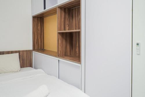 a bedroom with a bed and wooden cabinets at Premium Relaxing 2BR at Casa de Parco Apartment By Travelio in Samporo