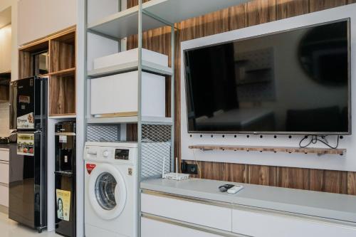 a kitchen with a washing machine and a tv at Premium Relaxing 2BR at Casa de Parco Apartment By Travelio in Samporo