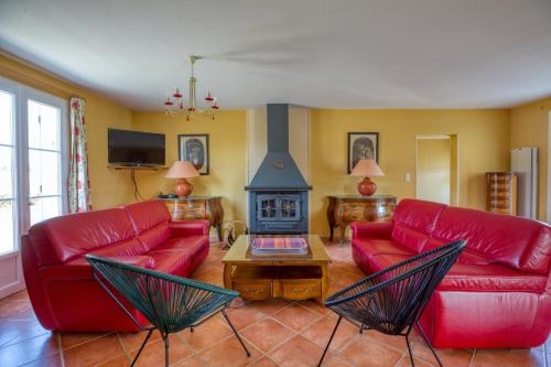 a living room with red couches and a fireplace at Maison confortable avec piscine à Villentrois-Faverolles 250m² in Faverolles