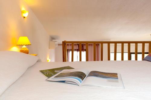 an open book on a bed with a lamp at Appartement charmant avec piscine à Porticcio - 32 m² in Porticcio