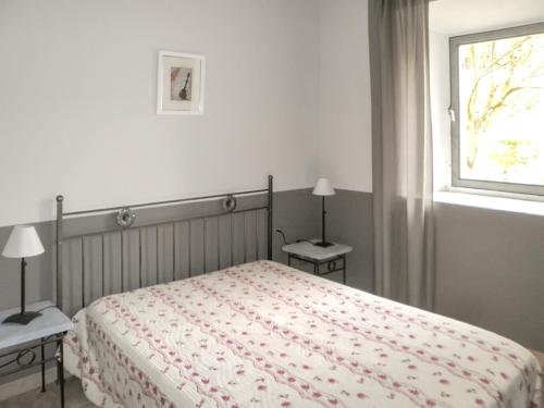 a bedroom with a bed with two nightstands and a window at Maison charmante à Oppède avec piscine partagée in Oppède