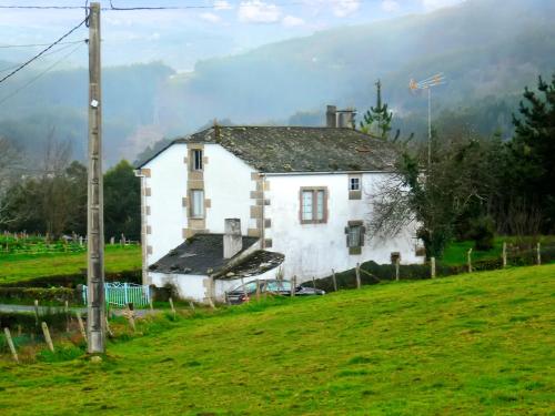 Ein weißes Haus auf einem Hügel auf einem Feld in der Unterkunft Charming house in Ourol with mountain view, large garden. in Merille