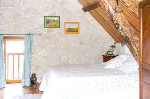 ein Schlafzimmer mit einem Bett und einer Steinmauer in der Unterkunft Maison de 2 chambres avec jardin clos et wifi a Villeuneuve sur Yonne in Beaujard