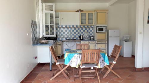a kitchen with a table and chairs and a refrigerator at Maison charmante à Gros-Morne + jardin in Gros-Morne