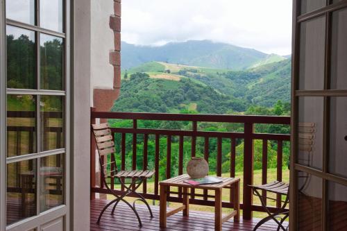 a balcony with a table and chairs and a view of mountains at Auberge Ostapé in Bidarray
