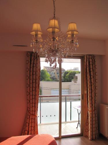 - une chambre avec un lustre et une grande fenêtre dans l'établissement Appartement moderne à Antibes - 50 m² - Vue sur jardin, à Antibes