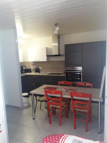 a kitchen with a table and red chairs in it at Appartement cosy avec piscine privée à Métabief - 38 m² in Métabief