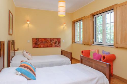 a room with two beds and a chair and windows at Sunny Villa in Comporta with Private Pool in Montalvo