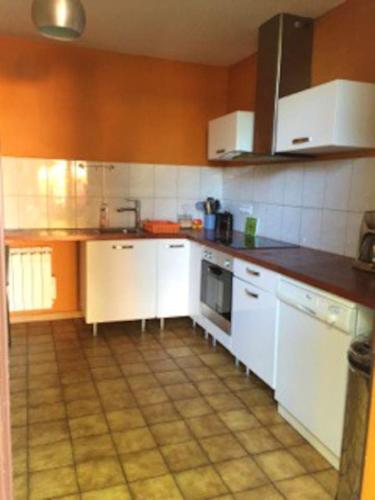 une cuisine avec des armoires blanches et un sol carrelé dans l'établissement Appartement confortable à Roanne avec jardin et parking, à Roanne