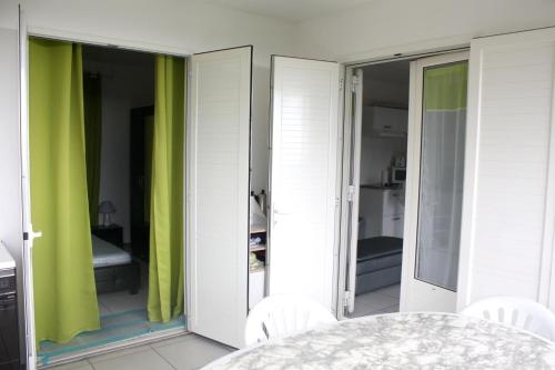 una habitación con mesa y una habitación con cortinas verdes en Maison d'une chambre avec vue sur la mer jardin clos et wifi a Saint Paul a 6 km de la plage, en Saint-Paul
