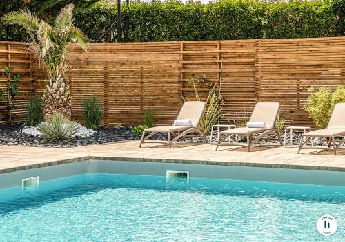 a swimming pool with two chairs and a fence at L'Initial in Toulouse