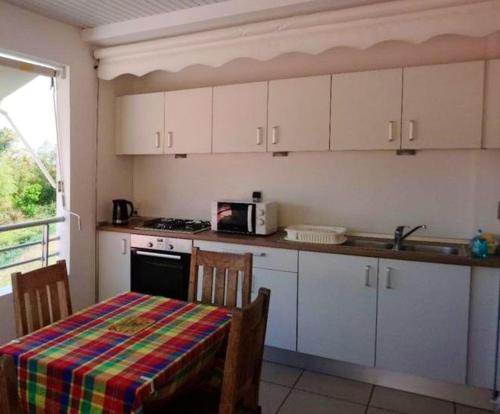 a kitchen with white cabinets and a table with a microwave at Studio avec vue sur la mer jardin amenage et wifi a La Trinite in La Trinité