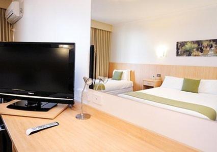 a bedroom with a large flat screen tv and a bed at Comfort Inn Capital Horsham in Horsham