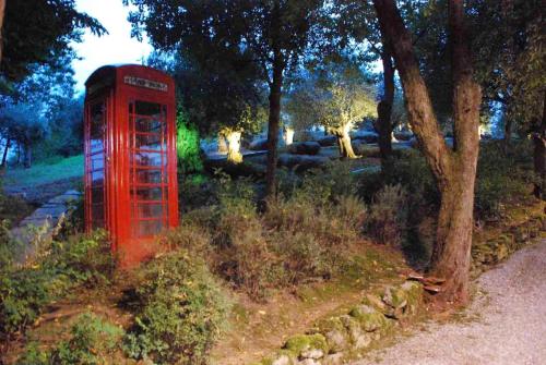 a red phone booth in a field with trees at Cozy Chalet in Castell'Arquato 90 m² with Private Pool in CastellʼArquato