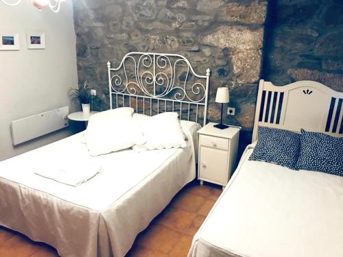 a bedroom with two beds and a stone wall at Spacious House in Molinaseca with Mountain View in Molinaseca