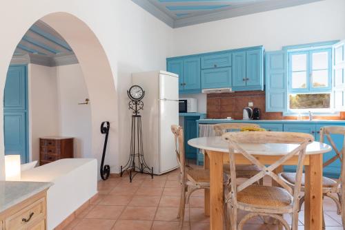 a kitchen with blue cabinets and a table with chairs at Patmos Studios in Skala