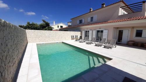 a swimming pool in front of a house at 4 bedrooms house with private pool and wifi at Aldeia dos Pinheiros in Azeitao