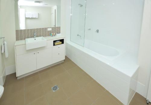 a white bathroom with a sink and a shower at Apartments G60 Gladstone in Gladstone