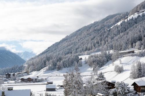 a snow covered mountain with houses and trees at Hotel Garni Hubertus-Nostalgie & Charme in Fulpmes