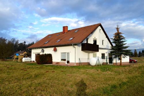 ein weißes Haus mit rotem Dach auf einem Feld in der Unterkunft Ferienwohnung Fabricio in Dolní Lánov