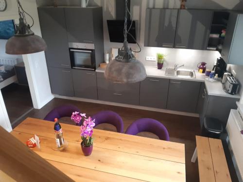 a kitchen with a wooden table and purple chairs at Tante Käthe in Nordstrand