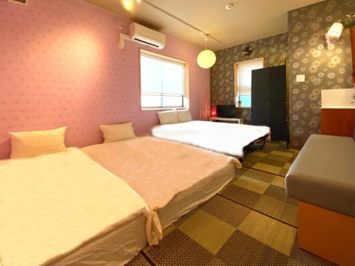 um quarto com duas camas e uma cadeira em Hostel Kay 101&102 em Osaka