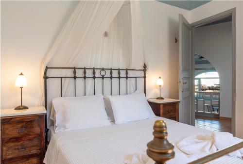 a bedroom with a bed with white sheets and two lamps at Patmos Studios in Skala