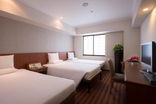 a hotel room with two beds and a flat screen tv at International Garden Hotel Narita in Narita