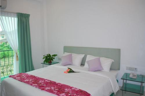 a bedroom with a white bed with purple pillows at MCITI Suites in Miri