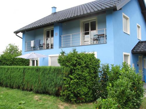 a blue house with a balcony and an umbrella at Villa Plavi Lav Potok in Potok