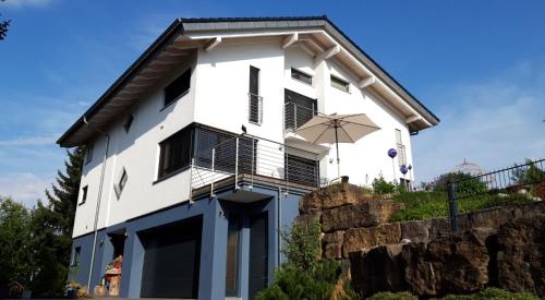 a white building with a balcony and an umbrella at Limes Apartment -übernachten am Limes- in Rainau