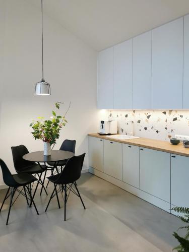 a kitchen with white cabinets and a table and chairs at Domki MODERN Jezioro Nyskie in Nysa