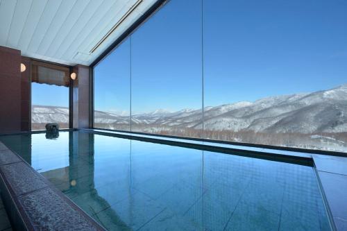 a swimming pool with a view of the mountains at Hotel Grand Phenix Okushiga in Yamanouchi