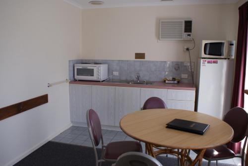 a kitchen with a table and a microwave and a refrigerator at Warrnambool Motel and Holiday Park in Warrnambool