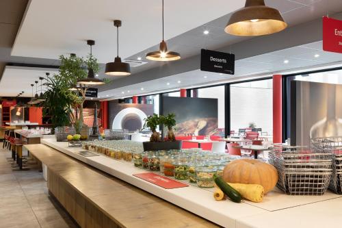 a long counter in a restaurant with a display of food at ibis Paris CDG Airport in Roissy-en-France
