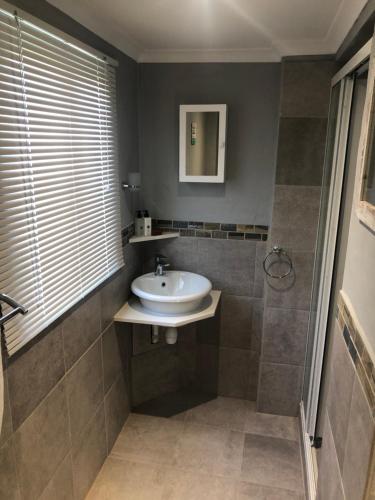 un baño con lavabo y ducha en Mimosa Cottage - Perfect Break-Away!, en George