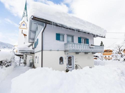a house covered in snow next to a church at Haus Salina in Ellmau