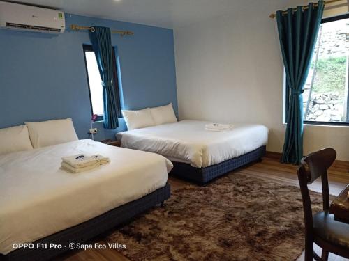 two beds in a room with blue walls at Sapa Eco Villas & Spa in Sa Pa