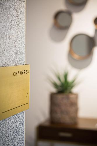 a sign on a wall with a plant on a table at Hotel Relais Saint Jean Troyes in Troyes