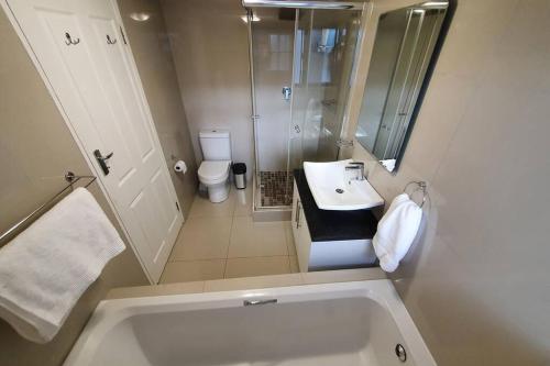 a bathroom with a tub and a sink and a toilet at LICORNA BEACH 51 UMHLANGA BEACHFRONT in Durban
