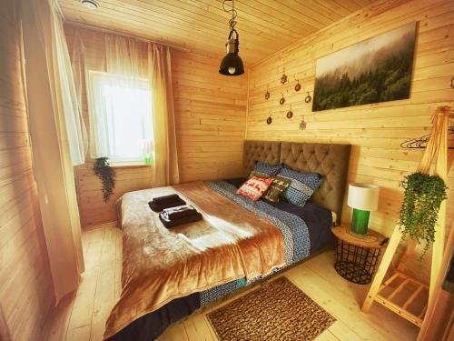 ein Schlafzimmer mit einem Bett in einer Holzhütte in der Unterkunft Lazy Deer - Camp in Staniszów