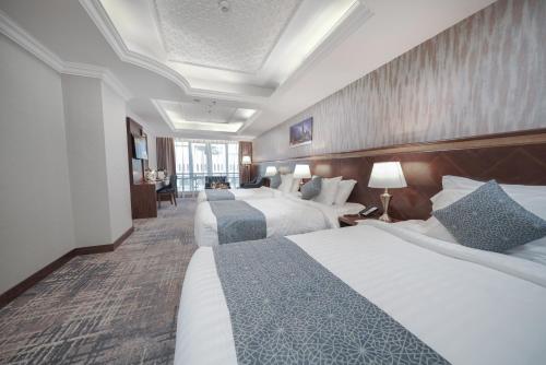a hotel room with two beds and a desk at MADEN Hotel in Al Madinah