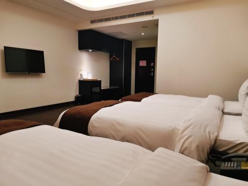 a hotel room with three beds and a flat screen tv at Hedu Hotel in Beigang